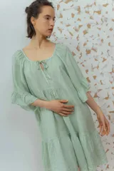 Vestido corto color beige de lino, con escote redondeado con lazo y mangas cortas amplias.