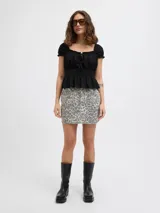 Minifalda de denim con estampado de leopardo en tonos grises, con cierre de cremallera y múltiples bolsillos.