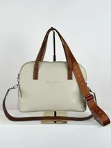 Cartera bandolera de cuero color crema con doble asa de mano marrón y correa larga de cinta con logo.