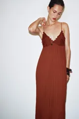 Vestido midi color ladrillo con tirantes finos, escote en pico y detalle de encaje en el busto. Tejido plisado y bajo asimétrico.