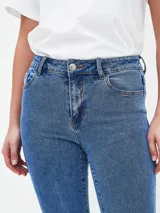 Jean de mezclilla azul de tiro alto, corte ajustado en muslos y pierna acampanada (estilo Oxford o flare).