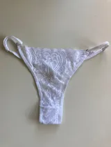 Bombacha colaless de encaje blanco con tiras ajustables en los costados.