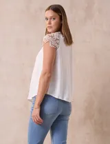 Blusa blanca de crepe marca Liv Los Ángeles, con hombros con aplique en crochet y espalda con abertura ojal y botones.