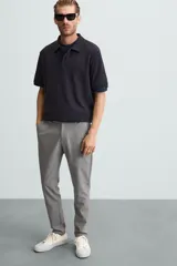 Pantalón largo de vestir gris claro con estampado de cuadros, corte slim fit y cintura elástica. Confeccionado en tejido con alta elasticidad, bolsillos frontales y cierre frontal con cremallera y botón.