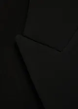 Blazer negro de corte recto, con cuello de pico cruzado y cierre de un solo botón. Presenta solapas con muesca, bolsillo de ribete en el pecho y dos bolsillos de solapa laterales.