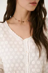 Camisa blanca con bordado floral, cuello en V y cierre frontal con botones.
