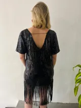 Vestido corto negro de lentejuelas con escote en V, mangas cortas y flecos en el ruedo.