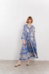 Vestido largo azul con estampado floral en tonos beige, confeccionado en viscosa. Presenta escote en V, botonadura completa en el frente y mangas largas con volados.