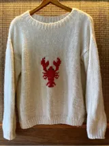 Sweater tejido de lana merino color crema, con cuello redondo y bordado de langosta roja en el centro.