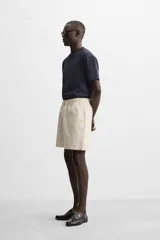 Bermuda negra regular fit confeccionada en tejido de algodón con estructura. Cintura elástica ajustable con cordón, bolsillos laterales y bolsillo trasero de vivo.