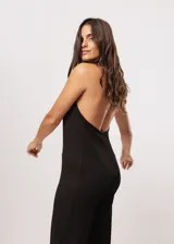Mono largo negro de punto con escote halter y corte palazzo. Incluye un collar largo con dijes de estrellas plateadas.