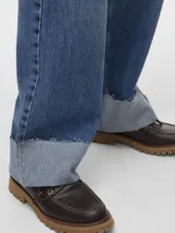 Jeans de mezclilla azul medio, tiro medio, corte recto y largo extra, con puños doblados y deshilachados en el borde.