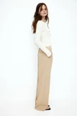 Pantalón color beige de lino con tiro alto, cintura elástica, bolsillos al bies y bolsillos traseros insertados. Piernas rectas con pliegue cosido adelante.
