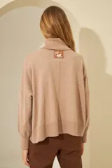 Sweater negro oversize de tejido de punto, con cuello alto y detalle de costuras a la vista.