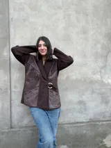 Chaqueta marrón de lana tejida con paneles de cuero texturizado, cuello acanalado, cierre con hebilla dorada y bolsillos laterales.