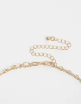 Collar corto dorado de doble cadena, una de eslabones y otra de cuentas facetadas color durazno. Incluye dijes colgantes de estrella, luna, corazón, ojo turco y medallones.