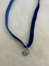 Gargantilla de terciopelo con dije plateado con forma de paloma.