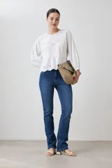 Blusa blanca con calados, cuello redondo, mangas largas abullonadas y corte peplum.