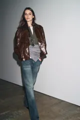 Chaqueta de Zara Woman Collection en tejido con acabado brillante efecto cuero. Presenta cuello solapa, manga larga con trabillas ajustables, bolsillos delanteros y cierre frontal con botones ocultos bajo solapa.