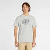 Remera de manga corta color gris melange con cuello redondo. Estampado frontal con la frase "More than a mile." y un dibujo lineal de cuatro zapatillas deportivas, con el logo de New Balance debajo.