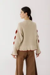 Sweater color gris claro con cuello redondo, mangas largas acampanadas y aberturas circulares en hombros y mangas con detalles de tela blanca.