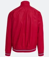 Chaqueta bomber roja de poliéster engomado, con cuello, puños y cintura acanalados a rayas blancas y azul marino. Tiene cierre frontal con cremallera y bolsillos laterales con cremallera.