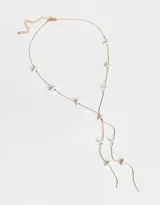 Collar largo dorado con cadena fina y colgantes de perlas nacaradas.