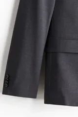 Blazer gris oscuro de botonadura sencilla, corte slim fit, con solapas de muesca finas, ojal decorativo, bolsillo superior, bolsillos delanteros con solapa, un bolsillo interior, cierre de dos botones, botones decorativos en los puños y abertura atrás.