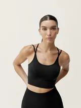Top deportivo negro de sujeción media, con tirantes finos cruzados y tejido microperforado en la espalda para mayor transpirabilidad.