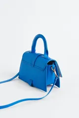 Cartera bandolera azul eléctrico de cuero sintético, con asa corta superior y correa larga extraíble. Tiene solapa con cierre magnético y detalle de hebilla metálica dorada.