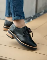 Zapato acordonado color bronce de cuero vacuno con perforaciones decorativas, taco de madera con folia en cuero de 4cm y entre suela de goma de 1,5cm. Horma de punta redonda y cómoda.