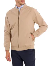 Campera bomber color beige de algodón orgánico con spandex, corte regular, cuello, puños y pretina acanalados, cierre frontal, bolsillos delanteros con solapa y broches ocultos, bolsillos internos y forro de franela.