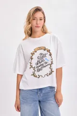 Remera blanca de corte amplio con estampado de Cenicienta y la frase 'The Right Shoe Makes the Difference'.