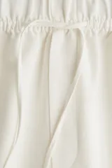 Pantalón tobillero de corte holgado en tejido liviano de mezcla de lino. Modelo de tiro alto con elástico revestido y cordón para ajustar fino en la cintura, bolsillos al bies y piernas ajustadas.