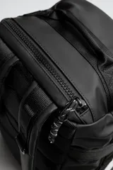 Mochila negra fabricada en tejido técnico. Tiene un compartimento principal con cierre mediante hebillas de liberación rápida y cremallera, un bolsillo interior con cierre, parte posterior acolchada con banda de sujeción para equipaje, dos asas de mano y dos asas de hombro ajustables.