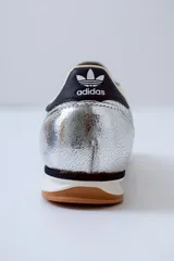 Championes Adidas SL 72 plateados con detalles en azul marino y suela de goma marrón.