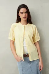 Camisa blanca de manga corta abullonada, cuello mao y botones forrados.