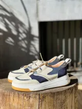 Zapatillas de cuero vacuno color blanco, con detalles en cuero metalizado celeste y gamuza azul oscuro.