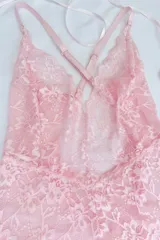 Body de encaje elastizado color rosado, con espalda baja y breteles elásticos regulables cruzados en la espalda.