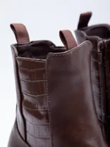 Bota de caña alta de símil cuero color marrón con plataforma de 7 cm y detalles de textura croco en los laterales.