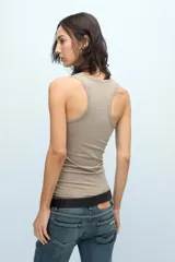 Musculosa blanca de algodón pima con lycra, calce fitted, escote en "U" y espalda deportiva. Detalle de cartera de botones a tono personalizados y bordado marcario a tono en el frente.