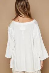 Blusa blanca de corte amplio, escote en V y mangas 3/4 con detalles de broderie.