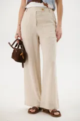 Pantalón de lino azul de corte palazzo con botón decorativo en la cintura.