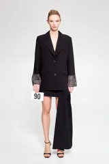 Blazer negro de corte clásico con solapas amplias y cierre de dos botones, con puños que presentan detalles brillantes.