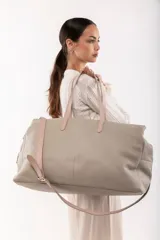 Bolso de viaje tipo weekender de cuero color marrón con doble asa de mano y correa bandolera ajustable y desmontable.