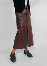 Pollera midi de cuero color borgoña, corte recto con abertura frontal y cierre con botón.