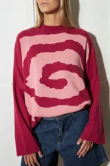 Sweater tejido de algodón color rosa y fucsia, con cuello redondo y diseño de espiral en el frente.