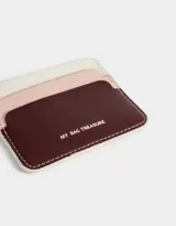 Tarjetero de cuerina con triple bolsillo colorblock en tonos blanco, rosa y bordó.