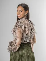 Camisa de seda italiana con estampado sutil de animal print en tonos tierra y beige. Diseño reversible con lazo que puede usarse en la espalda o al frente. Presenta volados en los hombros y mangas largas.