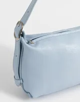 Bandolera color marrón camel de cuerina con textura gamuzada, asa corta de hombro y charm lateral.